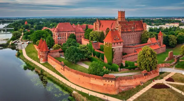 Malbork, największy zamek w Polsce, majestatycznie wznosi się nad rzeką Nogat. Potężne ceglane mury i liczne wieże świadczą o jego bogatej historii.
