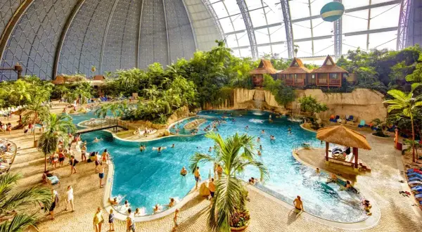 Wielki tropikalny basen pod kopułą, z palmami, domkami i ludźmi. Sprawdź nasz tropical island cennik!