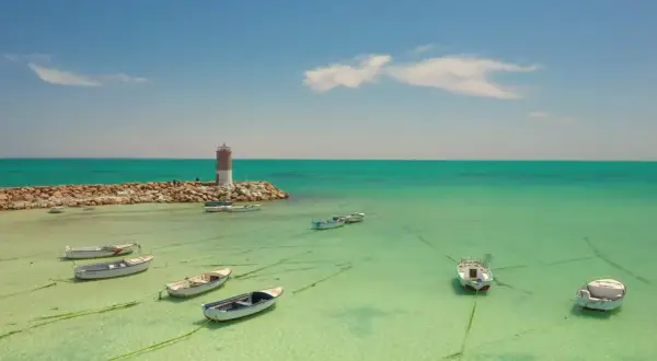 Idealne djerba wakacje: spokojne morze, łodzie kołyszące się na wodzie i latarnia morska.