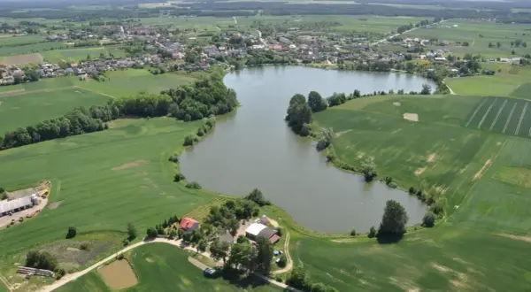 Widok z lotu ptaka na jezioro, pola uprawne i zabudowania w Przechlewie.