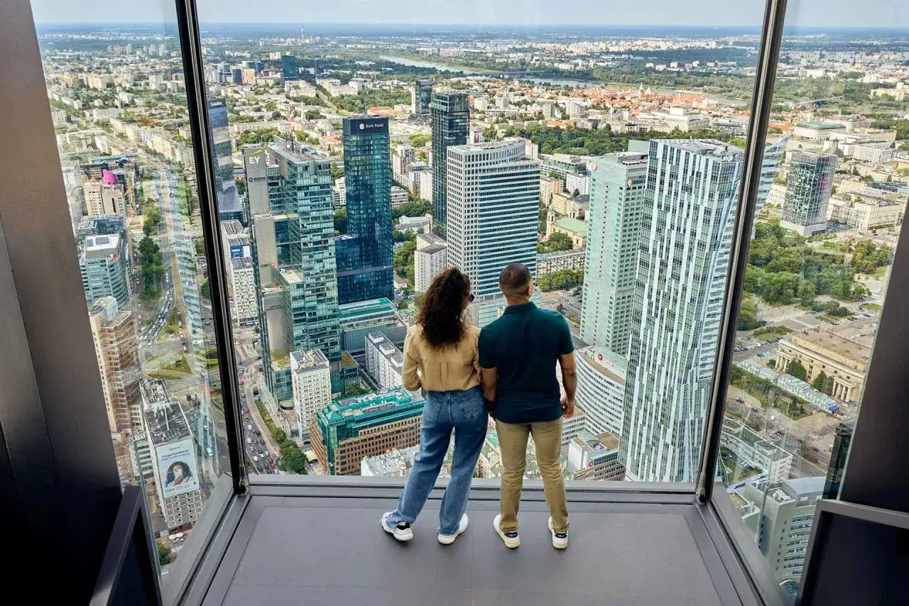 Para zwiedzająca Varso Tower taras widokowy, podziwia panoramę Warszawy.